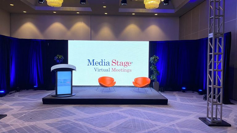 Stage with the high screen in the middle, two red chairs for the speakers.